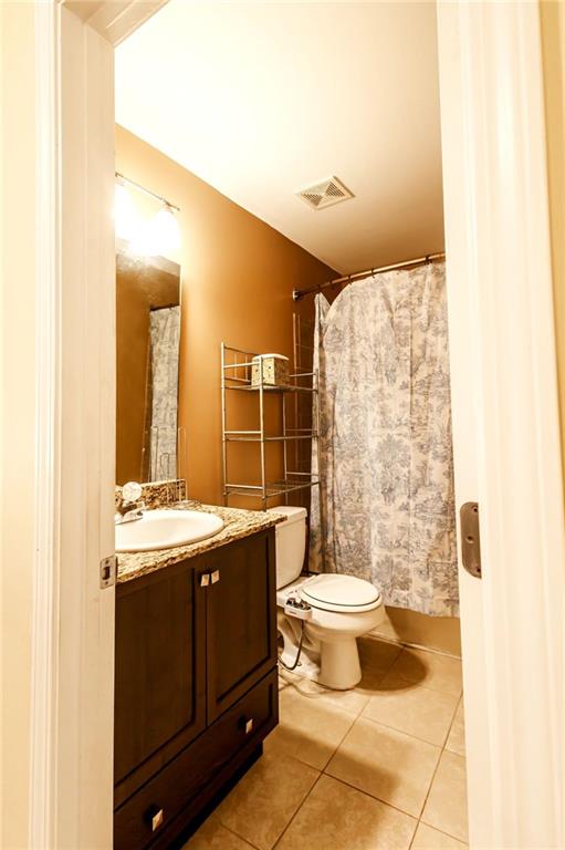 bathroom with toilet, vanity, and tile patterned flooring