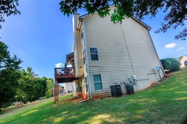 rear view of property featuring a wooden deck, a lawn, and central AC