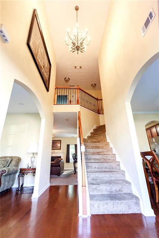 staircase with hardwood / wood-style flooring, a chandelier, and a towering ceiling