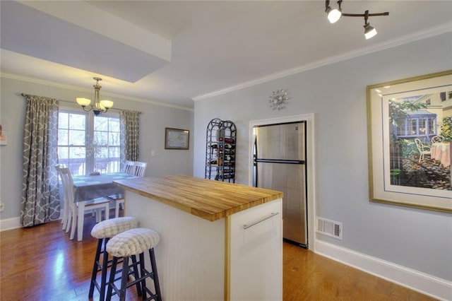 kitchen featuring visible vents, dark wood-type flooring, a center island, freestanding refrigerator, and pendant lighting