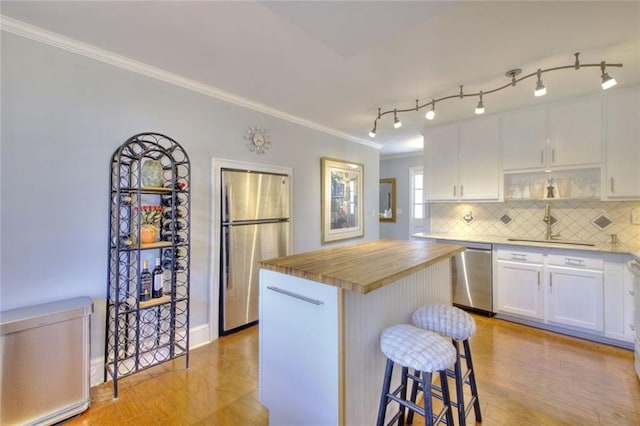 kitchen featuring a breakfast bar area, stainless steel appliances, white cabinets, wooden counters, and a center island