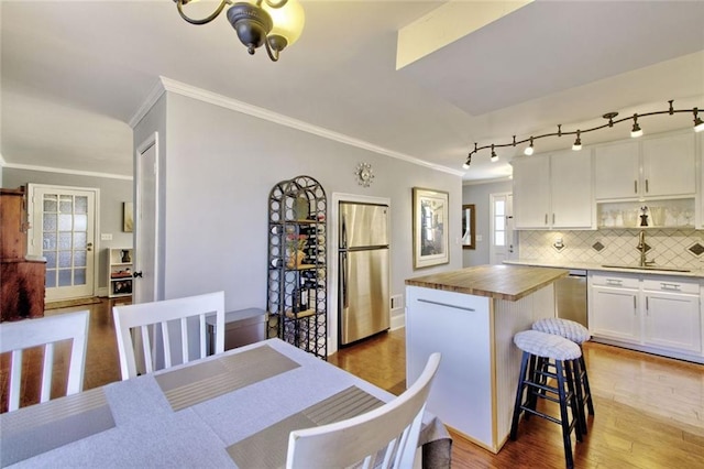 kitchen featuring a breakfast bar area, butcher block counters, a sink, white cabinets, and appliances with stainless steel finishes