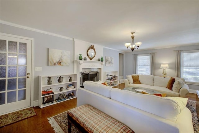 living area with a chandelier, ornamental molding, a fireplace, and dark wood finished floors