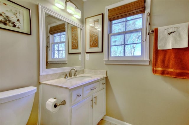 half bath featuring toilet, vanity, and baseboards