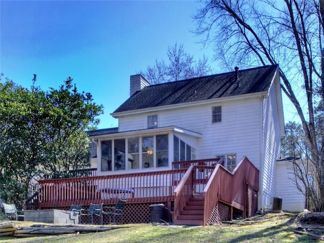 back of property featuring a yard, a chimney, a sunroom, a deck, and cooling unit