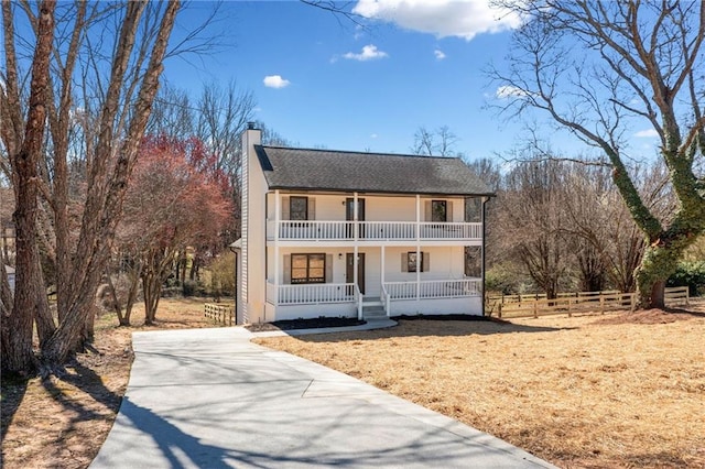 view of front facade featuring a porch, a chimney, fence, and a balcony