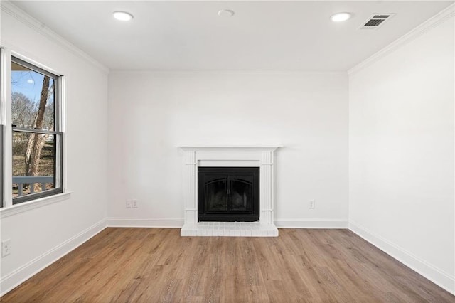 unfurnished living room featuring a fireplace with raised hearth, ornamental molding, visible vents, and baseboards