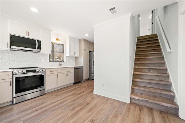 kitchen featuring stainless steel appliances, a sink, visible vents, light countertops, and backsplash