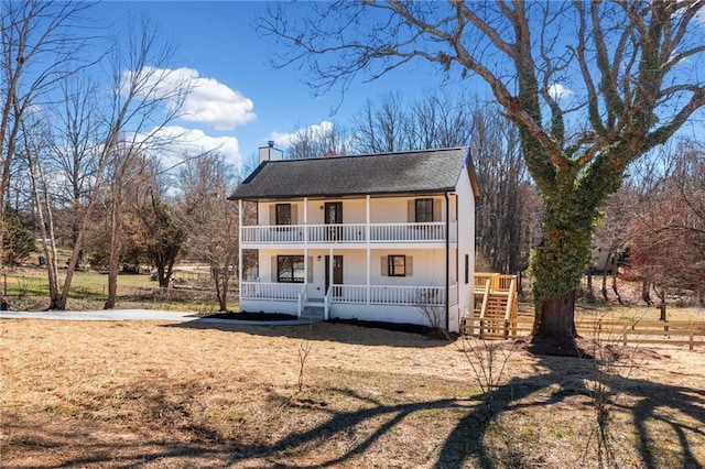 view of front of home with a balcony, a shingled roof, a chimney, and a porch