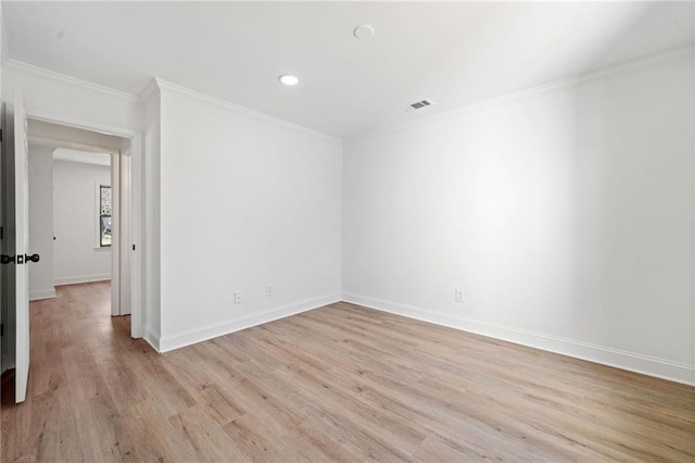 spare room featuring light wood-style floors, visible vents, ornamental molding, and baseboards