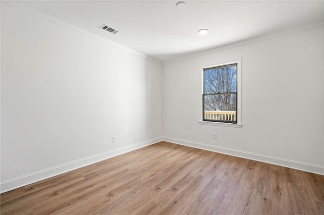 unfurnished room featuring baseboards, visible vents, wood finished floors, and ornamental molding