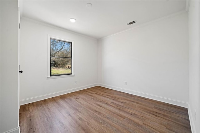 spare room featuring visible vents, crown molding, baseboards, and wood finished floors