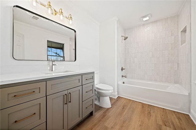 full bathroom featuring toilet, wood finished floors, visible vents, vanity, and tub / shower combination