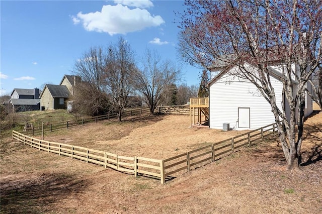 view of yard with a rural view, fence, and central air condition unit