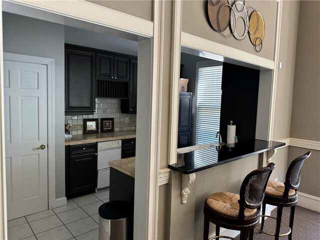 426 Pembrooke Cir Unit 426, Alpharetta, GA 30004 - kitchen featuring a kitchen breakfast bar, light tile patterned floors, backsplash, light countertops, and dark cabinetry