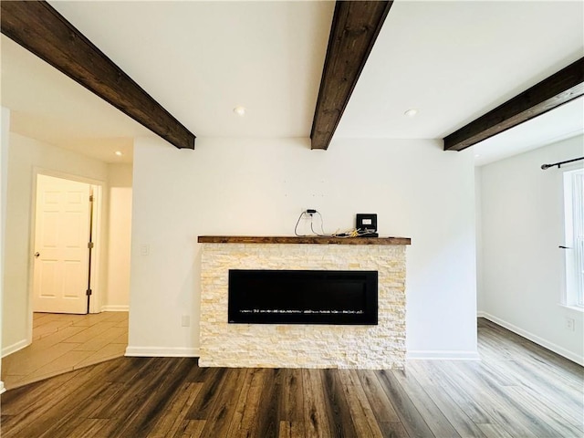 unfurnished living room with beam ceiling, hardwood / wood-style flooring, and a fireplace