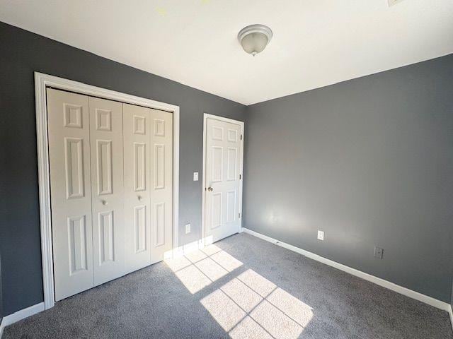 unfurnished bedroom with light colored carpet and a closet