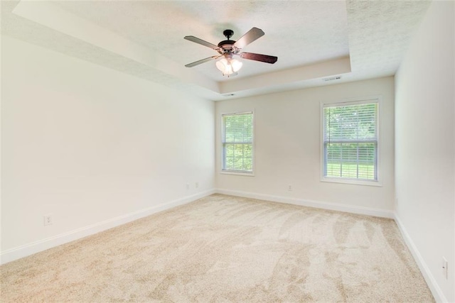 221 Glenview Trl, Griffin, GA 30224 - carpeted empty room featuring a raised ceiling, healthy amount of natural light, a textured ceiling, and a ceiling fan