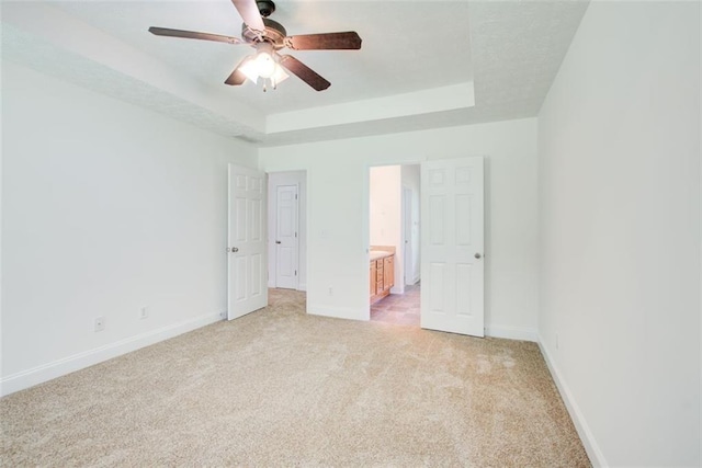 221 Glenview Trl, Griffin, GA 30224 - unfurnished bedroom with light colored carpet, a raised ceiling, connected bathroom, and a ceiling fan