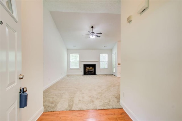 221 Glenview Trl, Griffin, GA 30224 - unfurnished living room featuring ceiling fan, a fireplace with flush hearth, light carpet, and light wood finished floors