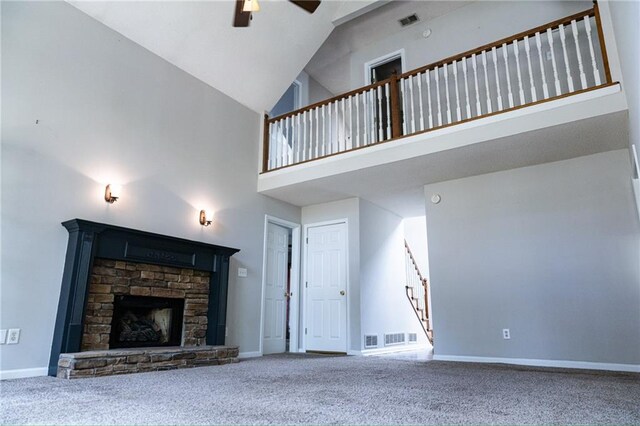 unfurnished living room with carpet floors, a stone fireplace, high vaulted ceiling, and ceiling fan