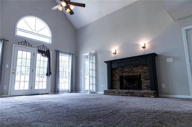 unfurnished living room featuring ceiling fan, high vaulted ceiling, carpet, and a stone fireplace