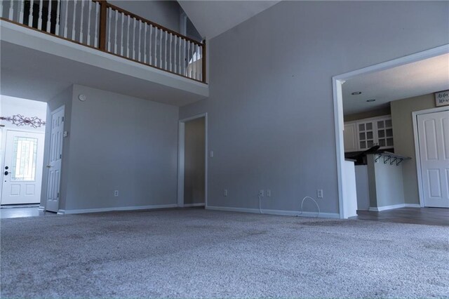 unfurnished living room with carpet and high vaulted ceiling