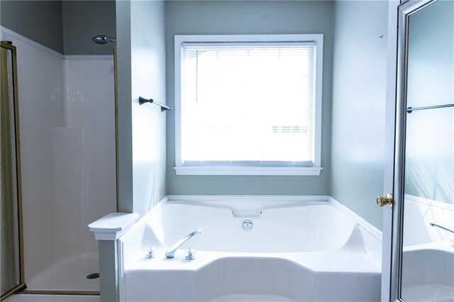 bathroom with shower with separate bathtub and a wealth of natural light