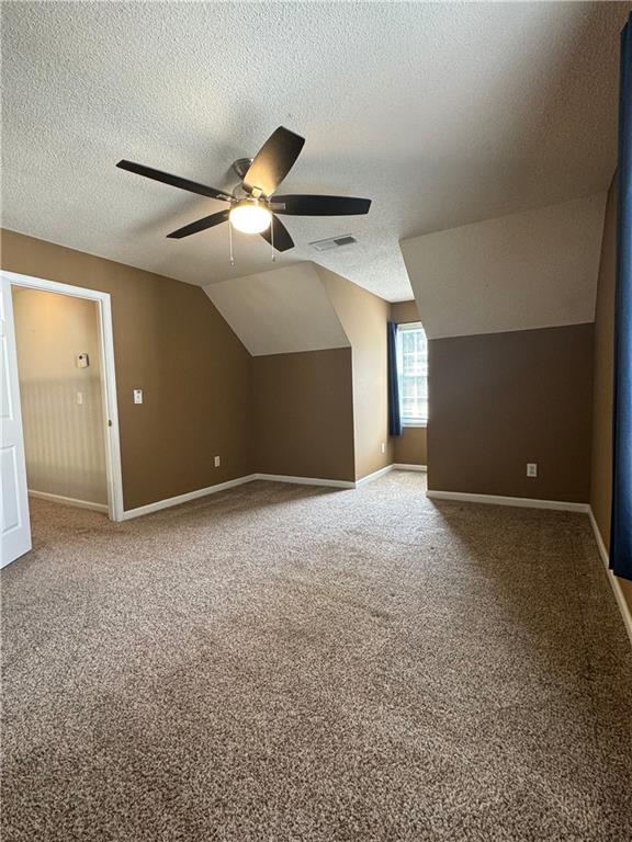 bonus room featuring a textured ceiling, ceiling fan, vaulted ceiling, and carpet flooring