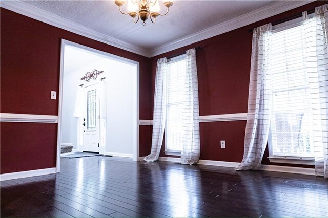 entryway with crown molding, a wealth of natural light, an inviting chandelier, and dark hardwood / wood-style floors