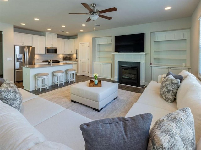 360 Hayden Cir, Woodstock, GA 30189 - living room with a ceiling fan, wood finished floors, a glass covered fireplace, built in features, and recessed lighting