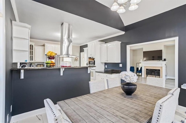 kitchen featuring ornamental molding, white cabinets, stainless steel microwave, and a peninsula