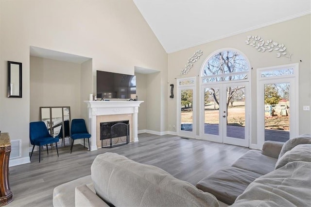 living area featuring visible vents, wood finished floors, french doors, a fireplace, and high vaulted ceiling