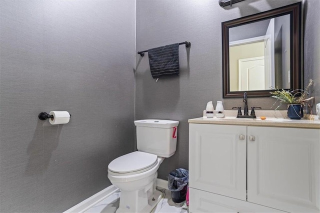 bathroom featuring toilet, marble finish floor, baseboards, and vanity