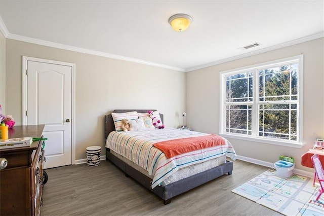 bedroom with baseboards, visible vents, crown molding, and wood finished floors