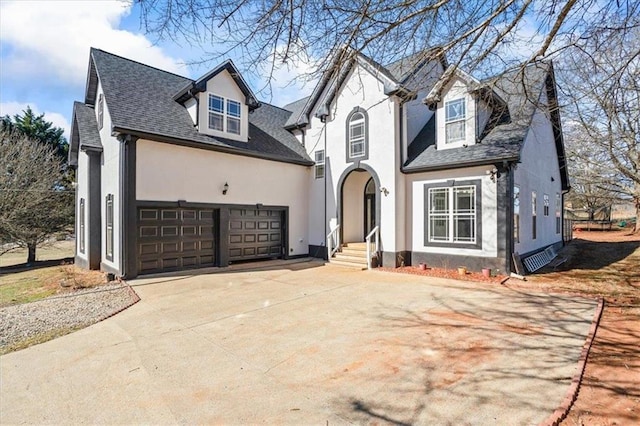 view of front of house with roof with shingles, driveway, an attached garage, and stucco siding