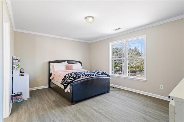 bedroom with visible vents, baseboards, wood finished floors, and ornamental molding