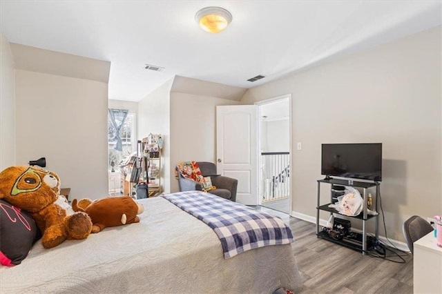 bedroom with wood finished floors, visible vents, and baseboards