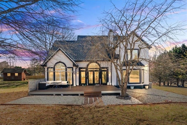 rear view of house with an outbuilding, a deck, an outdoor hangout area, a lawn, and a storage unit