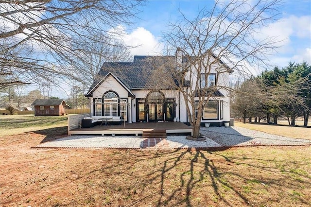 back of property with an outdoor structure, a lawn, a wooden deck, and a shed