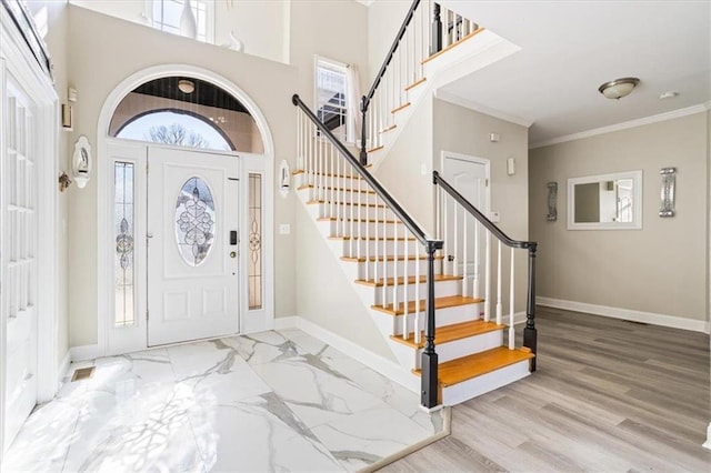 entrance foyer with stairs, a high ceiling, baseboards, and crown molding