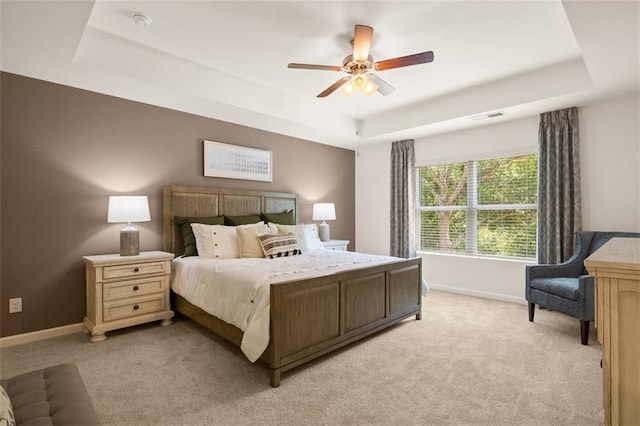 carpeted bedroom featuring ceiling fan and a tray ceiling