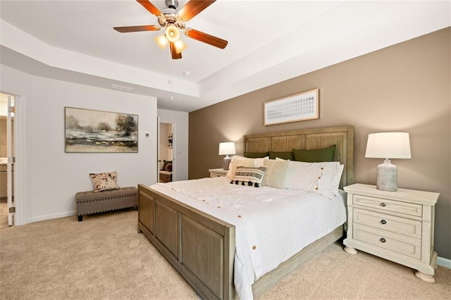 carpeted bedroom featuring a tray ceiling and ceiling fan