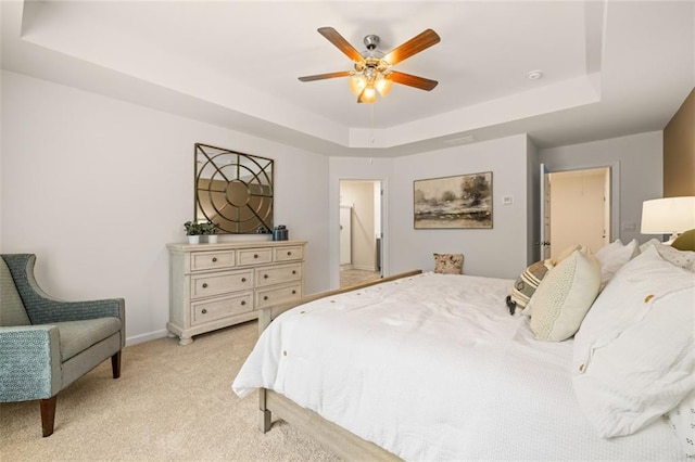 bedroom featuring light carpet, ceiling fan, and a tray ceiling