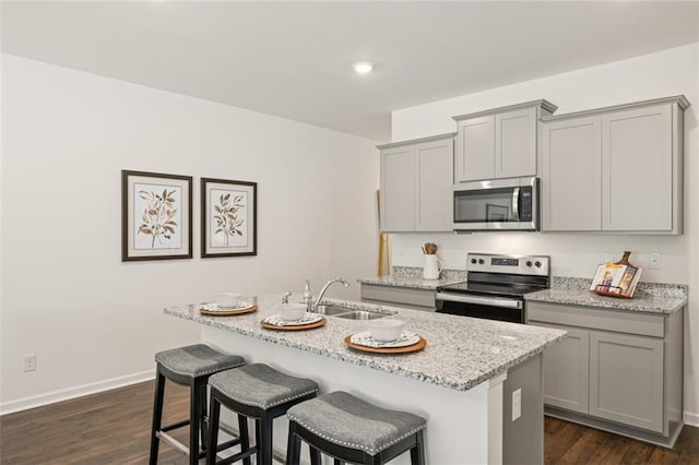 kitchen with stainless steel appliances, sink, a kitchen island with sink, and gray cabinets