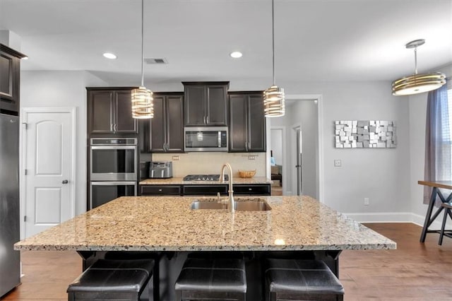 2953 Balvenie Pl, Acworth, GA 30101 - kitchen featuring appliances with stainless steel finishes, a sink, light stone counters, a kitchen breakfast bar, and baseboards
