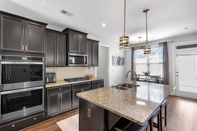 2953 Balvenie Pl, Acworth, GA 30101 - kitchen featuring appliances with stainless steel finishes, a sink, a center island with sink, light stone countertops, and recessed lighting