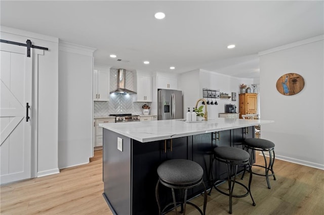 114 Narrows Loop, Waleska, GA 30183 - kitchen featuring wall chimney range hood, stainless steel appliances, a barn door, white cabinets, and a kitchen island with sink