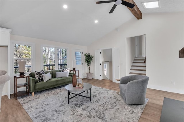 living area with light wood-style flooring, baseboards, beamed ceiling, a ceiling fan, and high vaulted ceiling