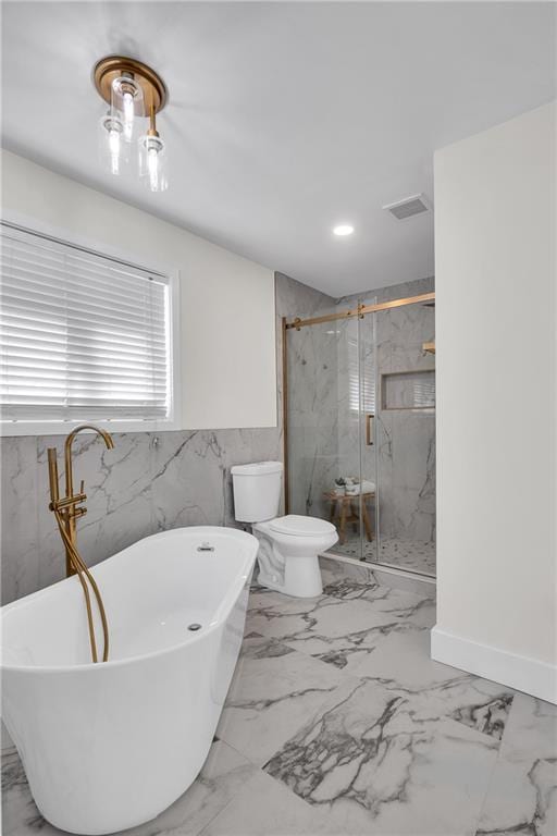 full bathroom featuring marble look tiles, a marble finish shower, a freestanding bath, and toilet